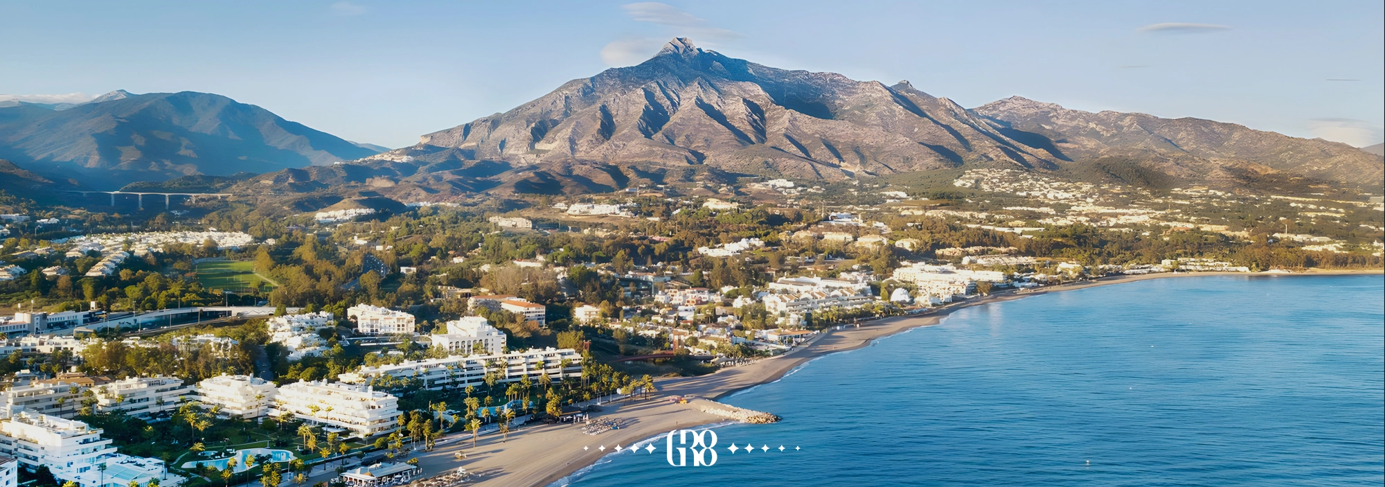 Whitewashed beach villas in Marbella during winter, with calm blue waters and empty sun loungers under soft sunlight